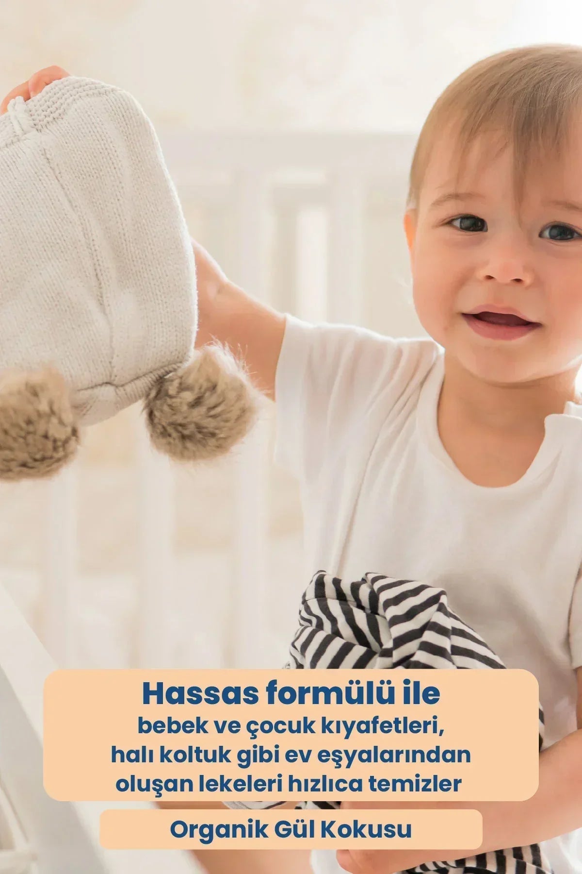 Bebek, beyaz bebek şapkası ve çizgili giysi tutuyor, hassas formüllü organik gül kokulu leke çıkarıcı reklamı