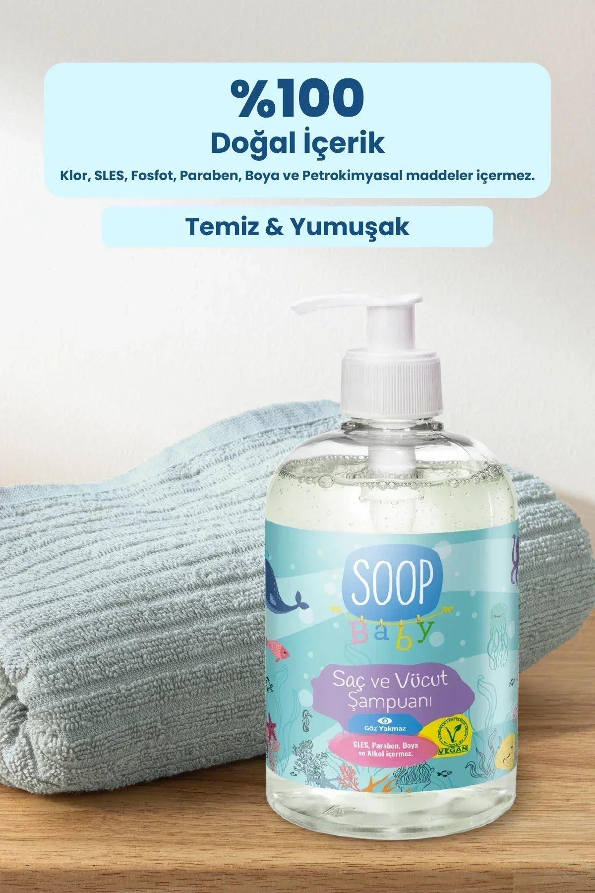 Soop Baby saç ve vücut şampuanı şeffaf pompalı şişede, mavi havlu üzerinde, doğal içerik etiketiyle